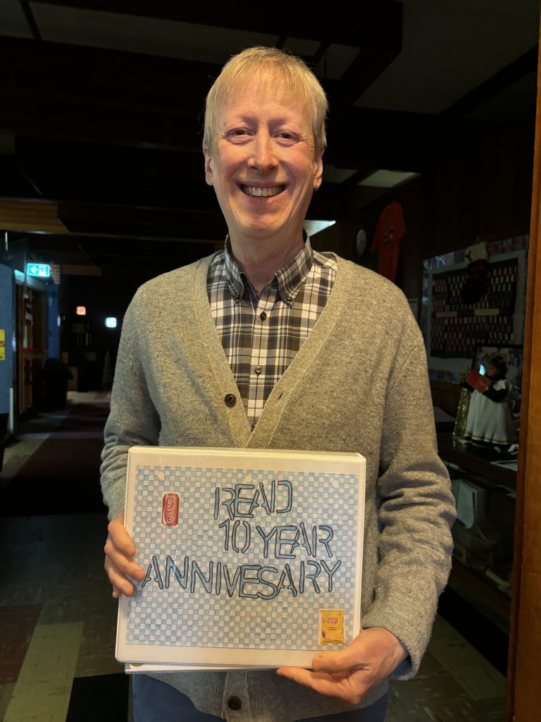 Rev. Read is holding the keepsake book for his 10th anniversary at Trinity-Anjou Pastoral Charge.